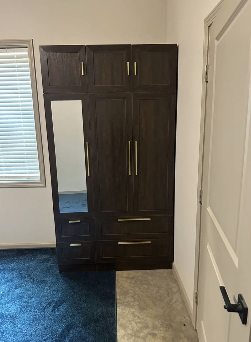 Dark brown wardrobe with a mirrored door, gold handles, upper cabinets and lower drawers