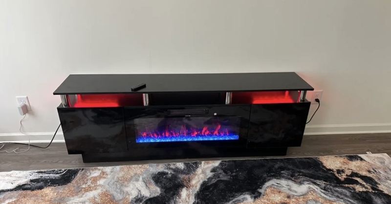 Black gloss entertainment center with a built-in electric fireplace and red accent lighting