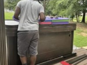 Installer working on the deck beside the hot tub during the gazebo assembly